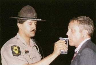 A highway patrol officer uses a Breathalizer field test to screen a driver for evidence of alcohol consumption. © Custom Medical Stock Photo.